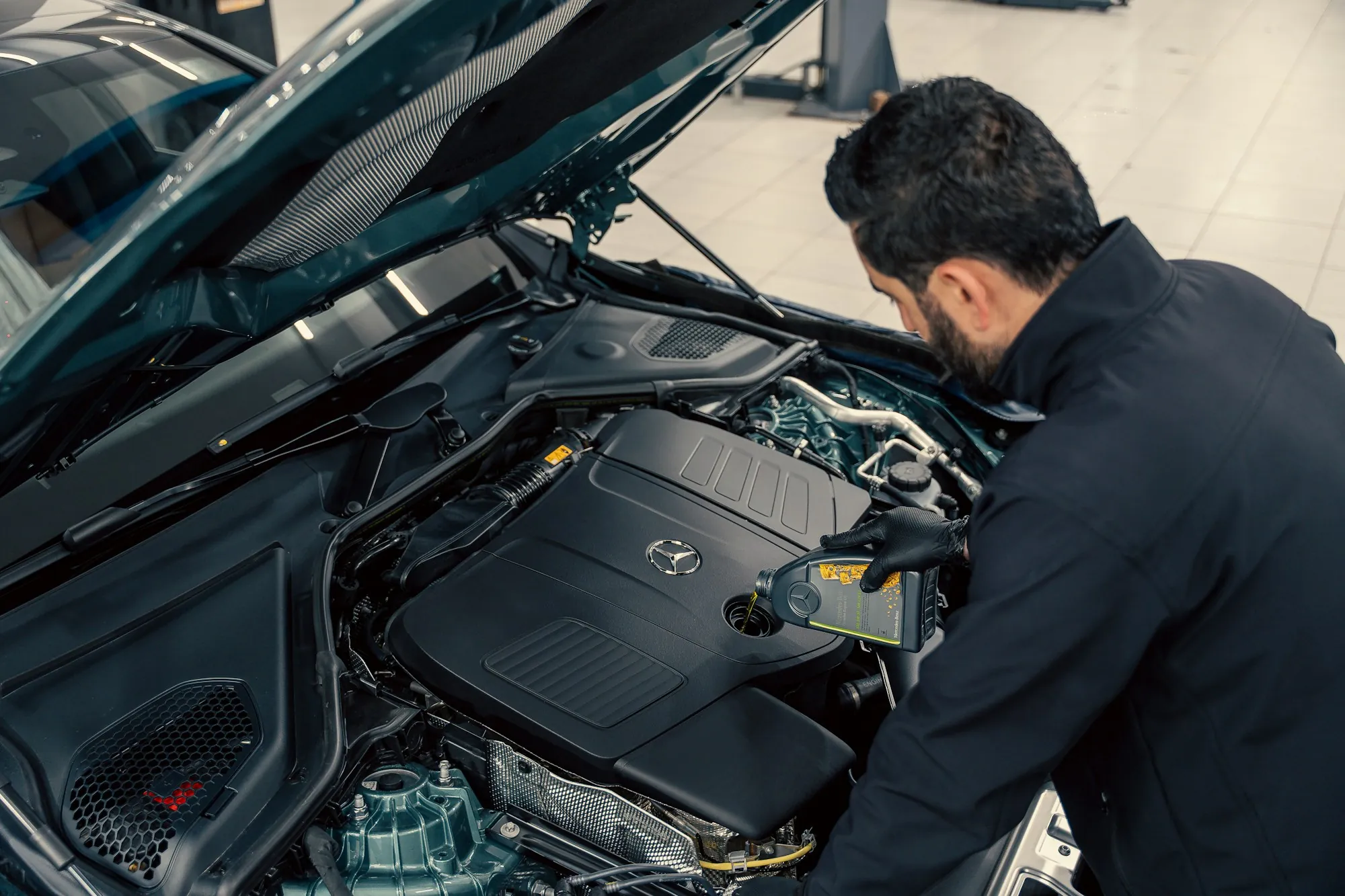Mechanic working on the engine of a car with the hood open